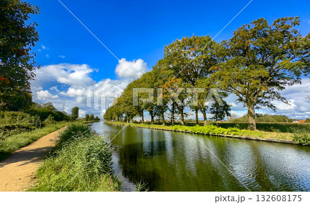 A Peaceful Riverside Scene Showcasing Lush Trees and a Vast, Clear Blue Sky Above 132608175