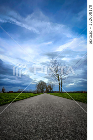 A Peaceful Pathway meandering through Nature beneath a Dramatic and Beautiful Sky above 132608179