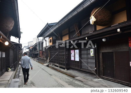 日本の岐阜県　高山市の古い町並　杉玉を飾る酒屋と散歩をする男性　春の高山祭期間中の朝の様子 132609540