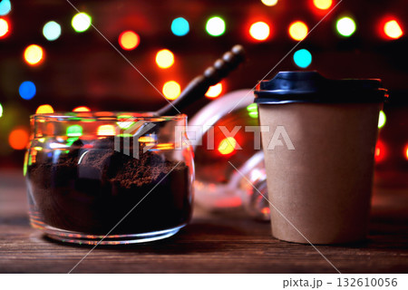 glass jar with ground coffee wooden coffee spoon paper cup on a natural wooden brown background with colored lights blurred foreground close-up copy space glass jar with ground coffee wooden coffee spoon paper cup on a natural wooden brown background with colored lights blurred foreground close-up copy space 132610056