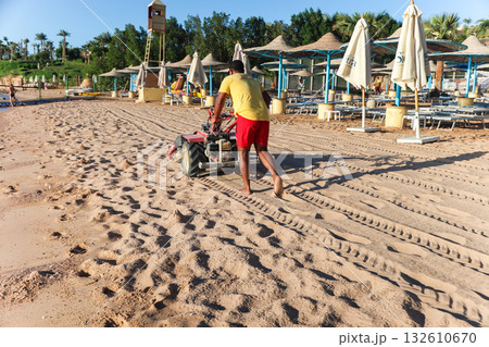 Egypt, Sharm el-Sheikh - September 26, 2025 A Savoy Hotel employee cleans sand on the beach early in the morning Egypt, Sharm el-Sheikh - September 26, 2025 A Savoy Hotel employee cleans sand on the beach early in the morning 132610670
