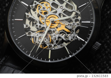 A close-up of a skeleton watch reveals intricate gears and metallic movement A close-up of a skeleton watch reveals intricate gears and metallic movement 132611583