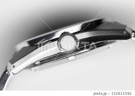 A detailed close-up of a polished wristwatch showing the knurled crown 132611592