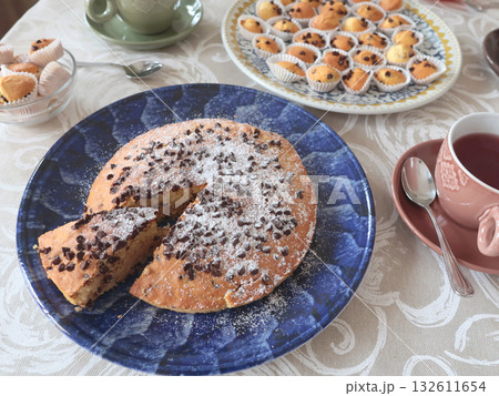 Chocolate chip cake on patterned ceramic plate. Holidays and lifestyle. Food on table covered with tablecloth.  132611654