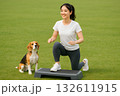 ステップ台運動をする女性と見上げるビーグル 132611915