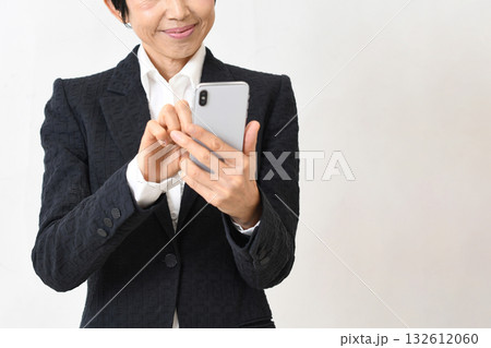 スーツ姿のアジア人シニア女性がスマホ操作 スーツ姿のアジア人シニア女性がスマホ操作 132612060