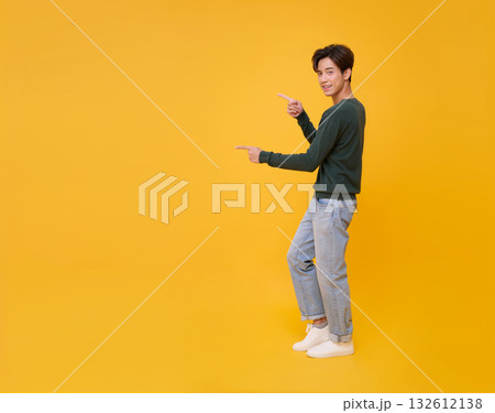 Copy space choice concept cheerful Asian man presenting pointing finger on yellow background for ad banner, product mockup, decision making, and marketing design. 132612138