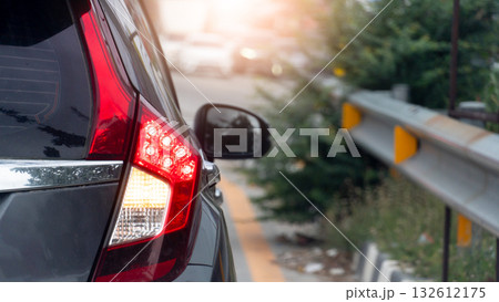 Rear side of grey car close up taillight on the road. Traffic barrier with grass and trees growing on the sides. Blurred of many car on the opposite road. Rear side of grey car close up taillight on the road. Traffic barrier with grass and trees growing on the sides. Blurred of many car on the opposite road. 132612175