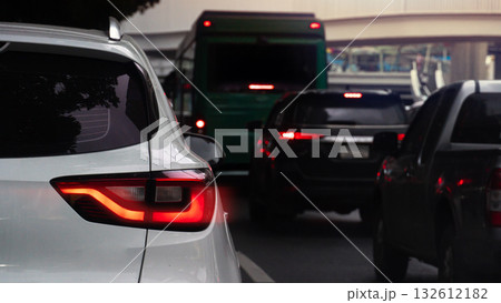 Rear side of white car with turn on brake light. Traffic jam on the asphalt road in the ciy at evening. Rear side of white car with turn on brake light. Traffic jam on the asphalt road in the ciy at evening. 132612182