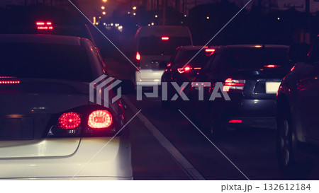 Abstract rear side of whtie car with turn on light. Traffic jam of car on the road in the city at night. Cars are parked in a queue with a long traffic line on the road. 132612184