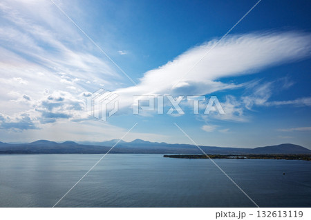 A large cloud is floating over a calm body of water 132613119