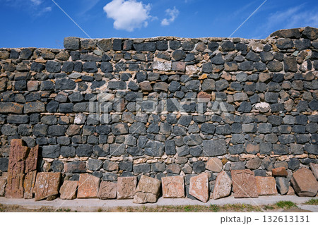 A wall made of stone blocks with a blue sky in the background A wall made of stone blocks with a blue sky in the background 132613131