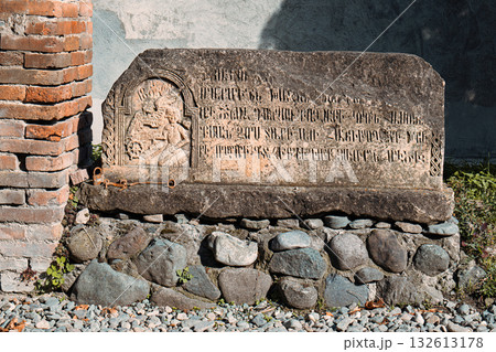 A stone slab with writing on it sits on a stone wall 132613178