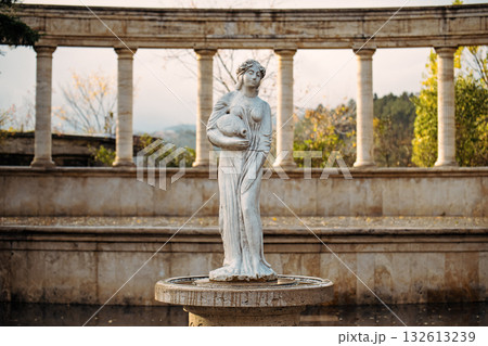 A statue of a woman holding a baby is standing in front of a fountain A statue of a woman holding a baby is standing in front of a fountain 132613239