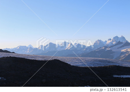 Snowcapped Mountain Range under Clear Morning Blue Sky captured at dawn. Serene majestic landscape vast expanse of rugged mountains, creating perfect backdrop nature lovers and outdoor enthusiasts Snowcapped Mountain Range under Clear Morning Blue Sky captured at dawn. Serene majestic landscape vast expanse of rugged mountains, creating perfect backdrop nature lovers and outdoor enthusiasts 132613541