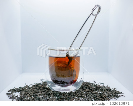 Glass Cup of Black Tea with Infuser and Loose Leaves on White Background 132613971