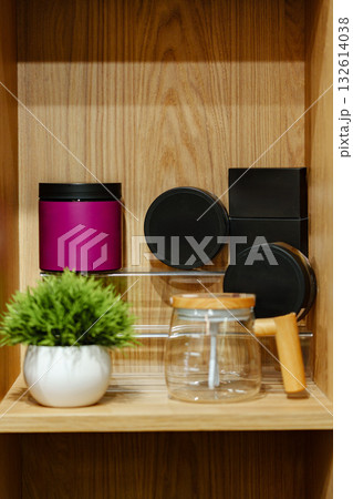 Stylish kitchen shelf featuring colorful canisters and modern glass kettle on a wooden surface 132614038