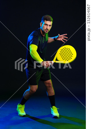 Practicing padel with a bright racket in a dramatic lighting setting 132614067
