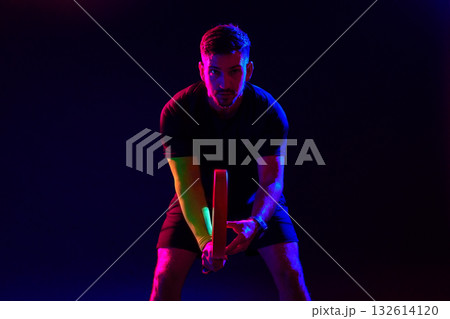 Athlete preparing to play table tennis in a dramatic dark setting with colorful lights 132614120