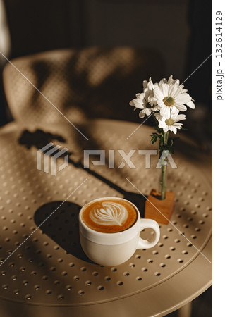 Enjoying coffee with flowers on a sunny table at a cozy cafe during the afternoon 132614129