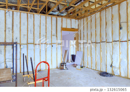 Construction work takes place in spacious room with insulation tools scattered around on floor. Construction work takes place in spacious room with insulation tools scattered around on floor. 132615065
