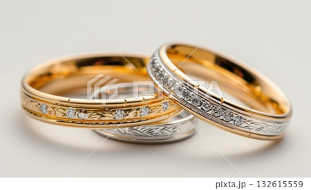 Close up of two wedding rings on a white surface, made of metal and gemstone Close up of two wedding rings on a white surface, made of metal and gemstone 132615559
