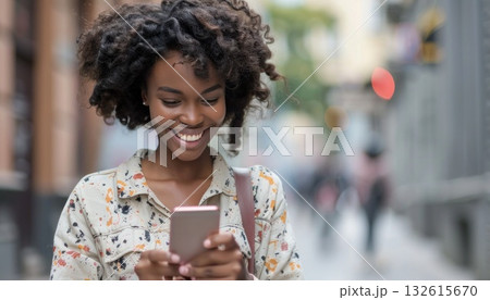 A woman with black hair and a Jheri curl smiling at her mobile phone 132615670