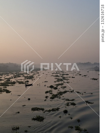 Aerial view of a vast, muddy landscape with scattered vegetation and a hazy sky at dusk 132616718