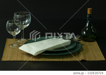 A green plate with a fork and spoon on it sits on a table with a napkin A green plate with a fork and spoon on it sits on a table with a napkin 132616724