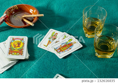 A deck of cards is on a table with a glass of whiskey and a bowl of cigarettes A deck of cards is on a table with a glass of whiskey and a bowl of cigarettes 132616835