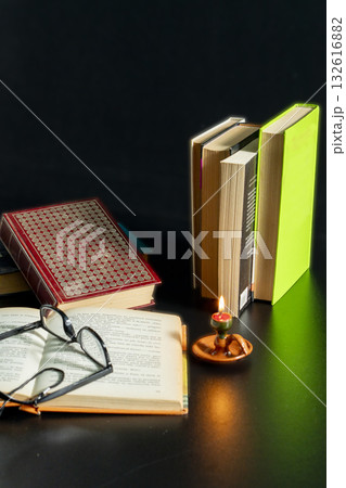 A stack of books with a candle on top of them 132616882