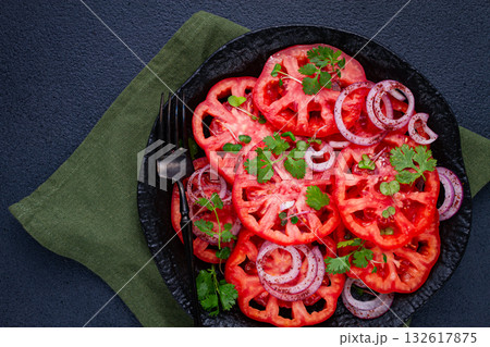 Freshly sliced tomatoes and red onions, garnished with herbs, on a black plate, summer salad, no people Freshly sliced tomatoes and red onions, garnished with herbs, on a black plate, summer salad, no people 132617875