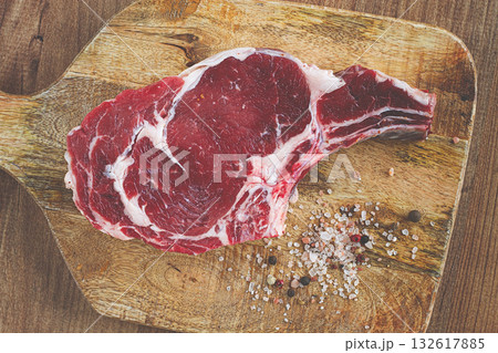 raw rib eye steak, cowboy steak, on a wooden chopping board, top view, no people, 132617885