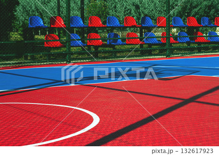 Bright basketball court with colorful seating in a sunlit outdoor setting Bright basketball court with colorful seating in a sunlit outdoor setting 132617923