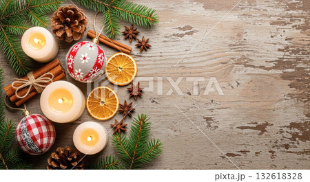 Festive holiday arrangement featuring candles, ornaments, pinecones, and dried oranges on rustic wooden surface, creating a warm seasonal atmosphere 132618328