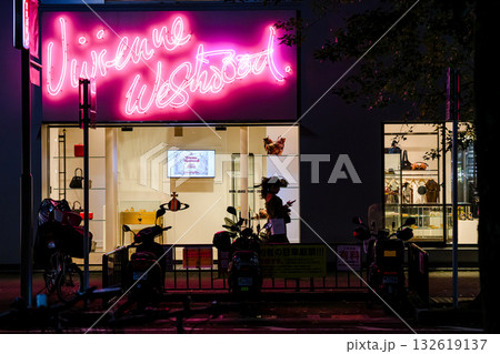 ネオンが輝く夜のファッションブティックと通行人のシルエット 132619137