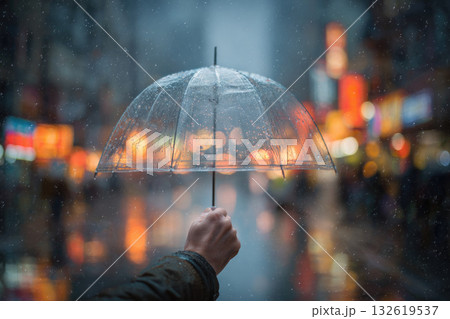 Hand holding transparent umbrella under soft city rain, blurred urban lights reflecting on wet street, evening atmosphere, cozy and peaceful mood Hand holding transparent umbrella under soft city rain, blurred urban lights reflecting on wet street, evening atmosphere, cozy and peaceful mood 132619537