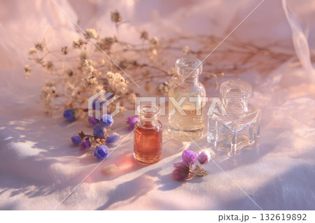 Glass bottle essential oil dried flower soft light natural aromatherapy relaxation wellness floral spa. Three glass bottles with essential oil and dried flowers soft fabric gentle sunlight creates 132619892