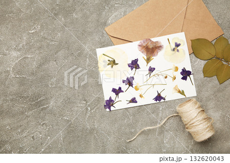 Pressed and dried flowers with twine on grey concrete background. For use in scrapbooking, floristry or herbarium. Pressed and dried flowers with twine on grey concrete background. For use in scrapbooking, floristry or herbarium. 132620043