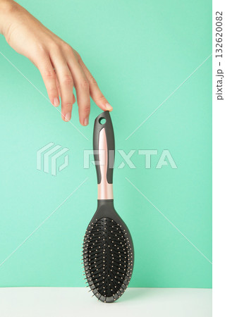 Woman hand holding hairbrush on mint background. Woman hand holding hairbrush on mint background. 132620082