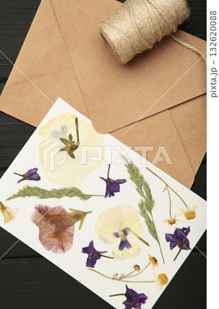 Pressed and dried flowers with twine on black wooden background. For use in scrapbooking, floristry or herbarium. 132620088
