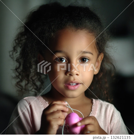 A cute dark-haired girl with brown eyes holds a small pink toy, her expression is sweet and curious 132621135