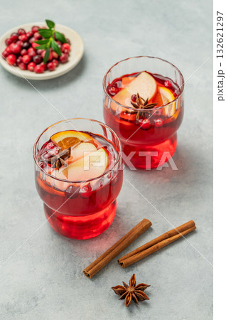 A cranberry drink in a glasses on a light background with cinnamon and berries. A cranberry drink in a glasses on a light background with cinnamon and berries. 132621297
