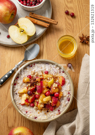 Overnight oatmeal with apple, cranberry and cinnamon in a plate on a wooden background with honey Overnight oatmeal with apple, cranberry and cinnamon in a plate on a wooden background with honey 132621319