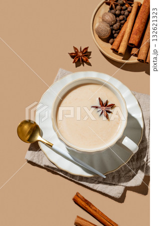 Traditional Indian masala chai tea with milk and spices in a cup on a beige background 132621323