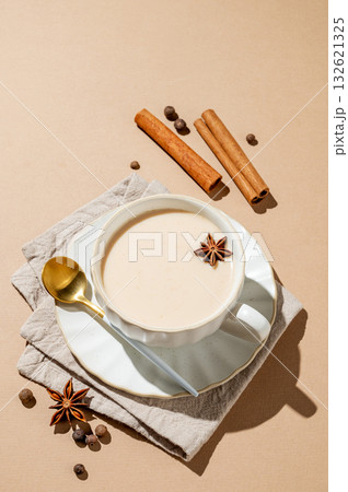 Traditional Indian masala chai tea with milk and spices in a cup on a beige background 132621325