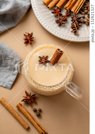 Traditional Indian masala chai tea with milk and spices in a cup on a beige background 132621327