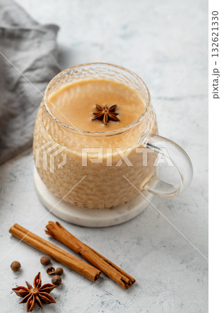 Traditional Indian masala chai tea with milk and spices in a cup on a light background with cinnamon 132621330