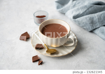 Hot chocolate in a cup on a light background with spices and napkin . Hot chocolate in a cup on a light background with spices and napkin . 132621345