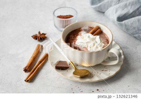 Hot chocolate in a cup with whipped cream and spices on a light background with napkin. Hot chocolate in a cup with whipped cream and spices on a light background with napkin. 132621346